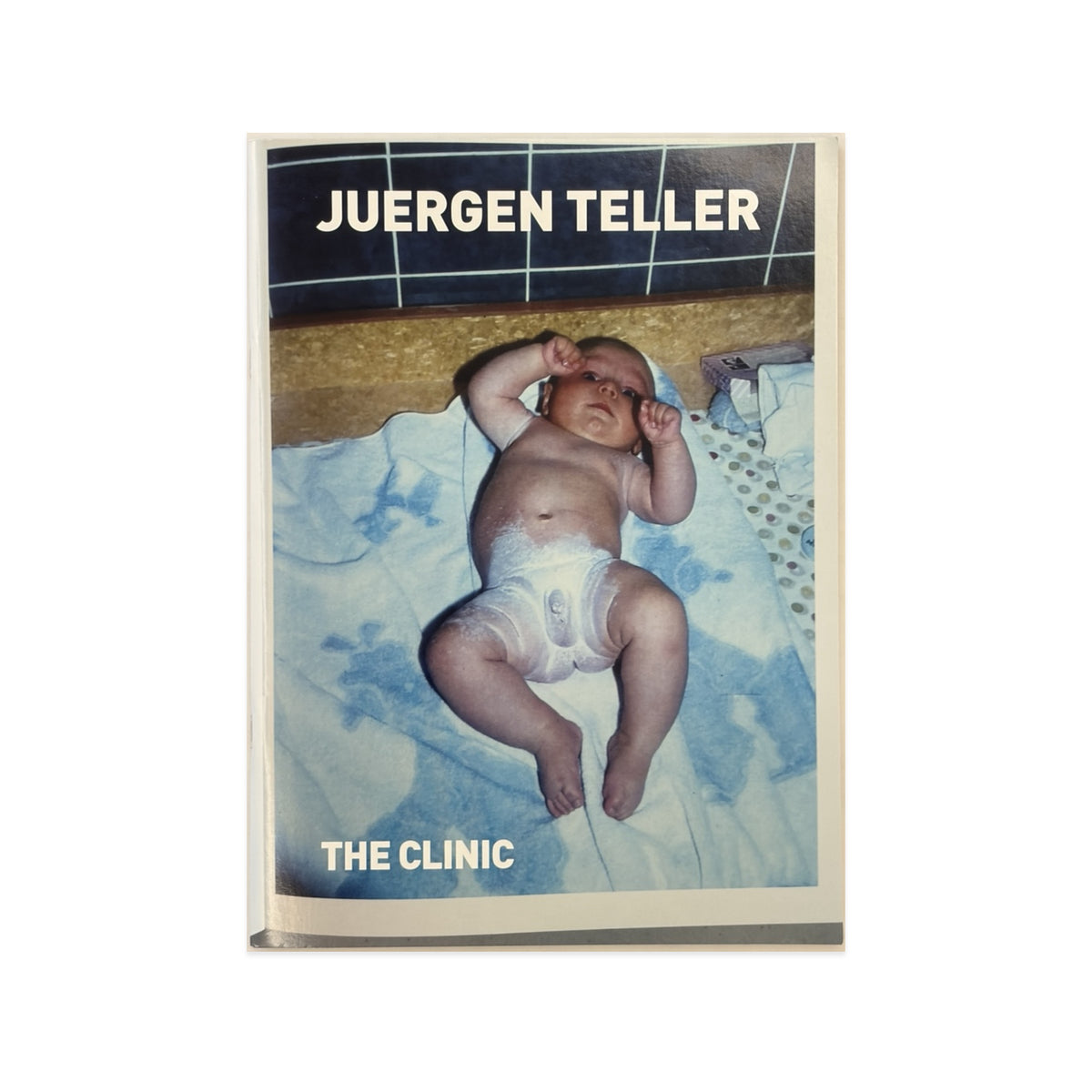 Couverture du livre Juergen Teller — The Clinic, montrant un nourrisson allongé sur un drap bleu